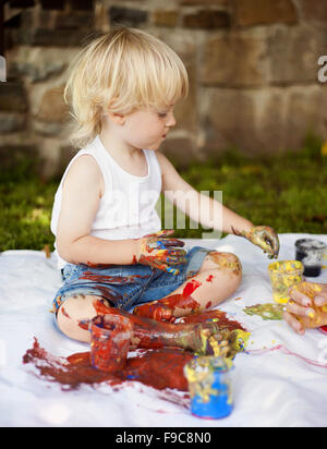 Cute child painting with vibrant colors in the garden Stock Photo