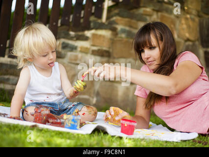 Cute child painting with vibrant colors in the garden Stock Photo