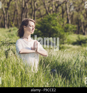 A young woman meditating in park Stock Photo