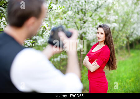 Photographer is taking photos of beautiful woman in red dress in nature Stock Photo
