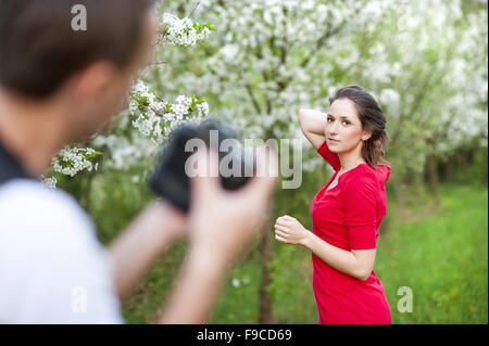Photographer is taking photos of beautiful woman in red dress in nature Stock Photo