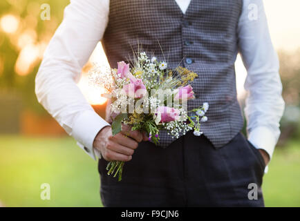 Part of the groom holding wedding bouquet in hand Stock Photo