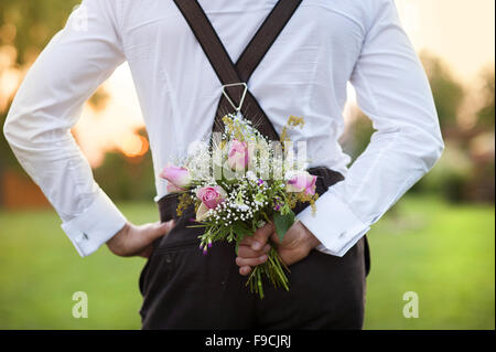 Part of the groom holding wedding bouquet in hand Stock Photo
