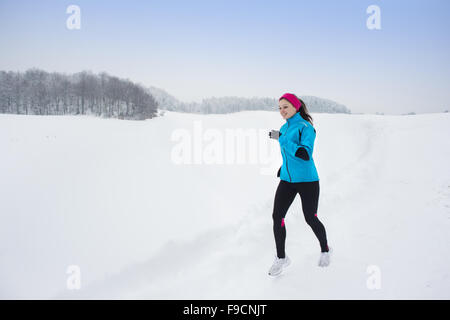 Athlete woman is running during winter training outside in cold snow weather. Stock Photo