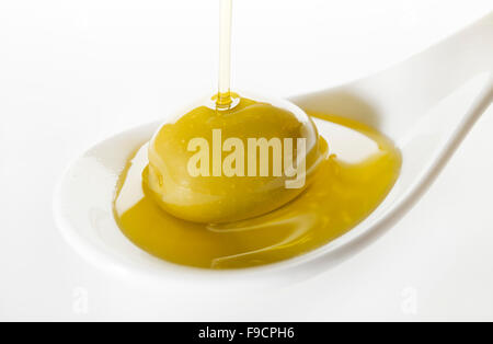 Virgin olive oil pouring on white spoon. Stock Photo