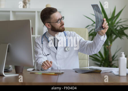 Thoughtful doctor holding chest and lungs xray in medical office Stock Photo