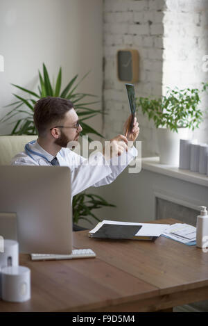 Thoughtful doctor holding chest and lungs xray in medical office Stock Photo