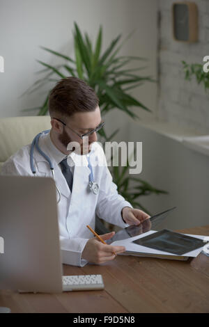 Thoughtful doctor holding chest and lungs xray in medical office Stock Photo