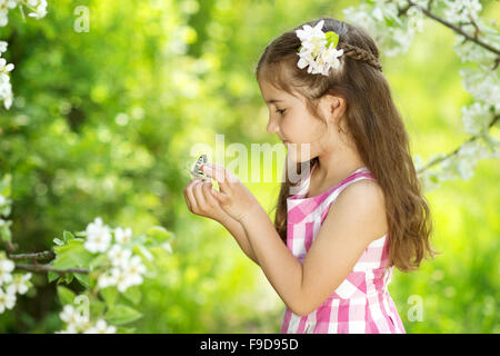Little girl is playing with butterfly in nature Stock Photo