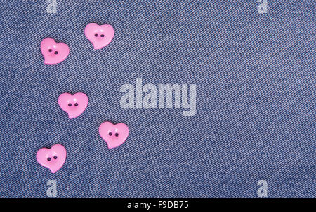 Pink buttons in the shape of hearts on jeans background Stock Photo
