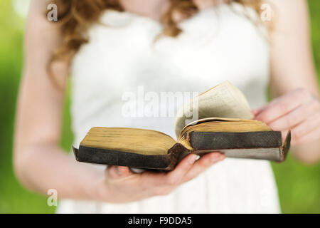 Beautiful woman with Bible is in sunny nature Stock Photo