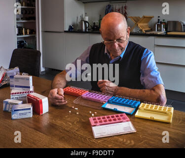 Senior elderly man sorting prescription medicine into pill boxes Stock Photo