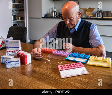 Senior elderly man sorting prescription medicine into pill boxes Stock Photo