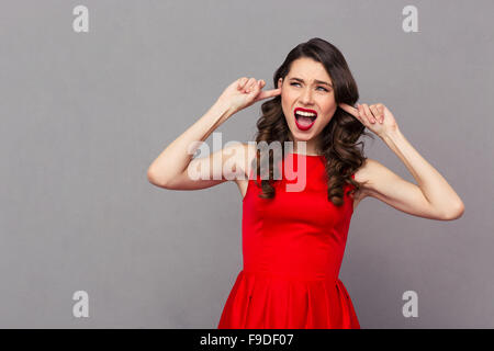 https://l450v.alamy.com/450v/f9df07/portrait-of-a-young-woman-in-red-dress-covering-her-ears-with-fingers-f9df07.jpg