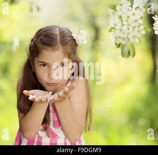 Cute little girl is holding flower outside in the green park Stock Photo