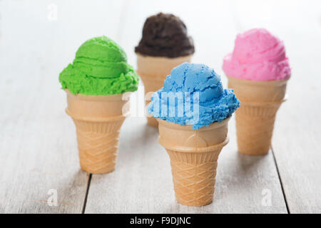 Blueberry, matcha, chocolate, and strawberry ice cream in the cone on white rustic wooden background. Stock Photo