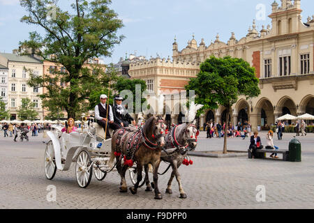 Tourists city tour horse-drawn carriage outside 13th century Sukiennice (the Cloth Hall or Drapers' Hall) in Market Square Krakow Poland Stock Photo