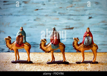 the three kings in their camels carrying their gifts for the Baby Jesus on a rustic nativity scene Stock Photo