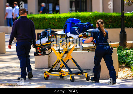 Paramedics pushing a gurny loaded with life saving equipment to a call out in downtown Santa Barbara, California Stock Photo
