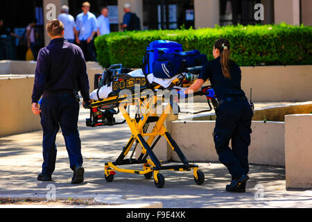 Paramedics pushing a gurny loaded with life saving equipment to a call out in downtown Santa Barbara, California Stock Photo