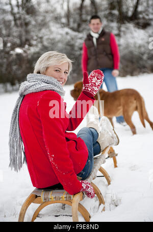Woman and man are having walk with dog in winter snowy countryside Stock Photo