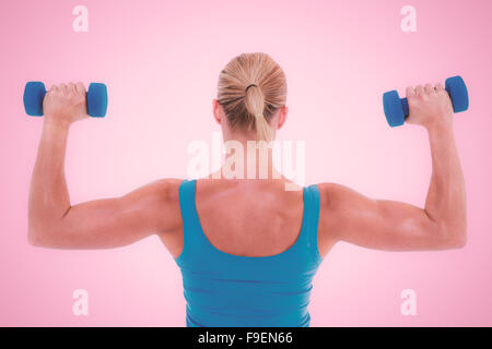 Composite image of rear view of muscular woman lifting dumbbells Stock Photo