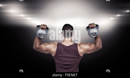 Composite image of rear view of a muscular man lifting kettlebells Stock Photo