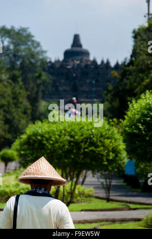 Man with straw hat walking towards Borobudur temple Stock Photo