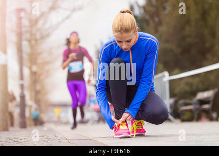 Young runner in the city race tying shoelaces Stock Photo