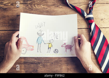 Fathers day composition with childs drawing and colorful tie laid on wooden desk backround. Stock Photo