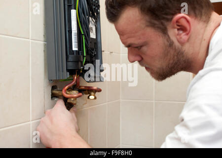 Plumber installs continuous-flow water heater in the bathroom Stock Photo