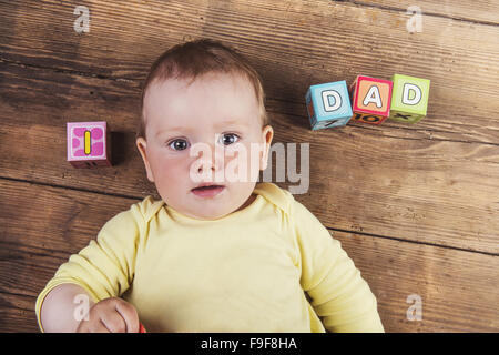 Little baby with cubes with dad sign on wooden background Stock Photo