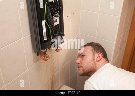 Plumber installs continuous-flow water heater in the bathroom Stock Photo