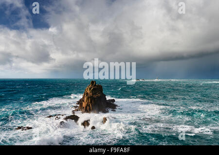 Huge seas crash around the Armed Knight rock formation at Lands End Cornwall Stock Photo