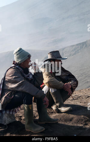 Two men resting and smoking a cigarette in front of mountain Stock Photo