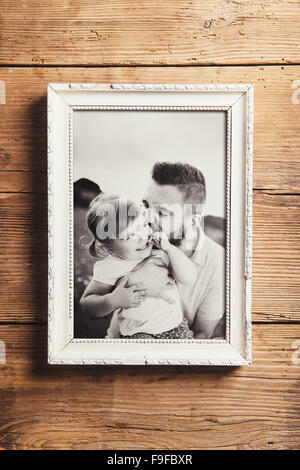 Family photo in white picture frame. Studio shot on wooden backgroung. Stock Photo