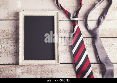 Rectangle picture frame and two ties laid on wooden floor backround. Stock Photo