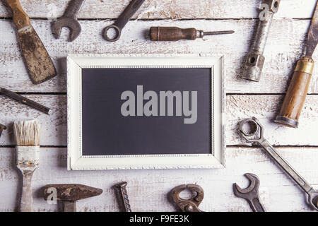 Empty picture frame and work tools. Studio shot on a wooden background. Stock Photo