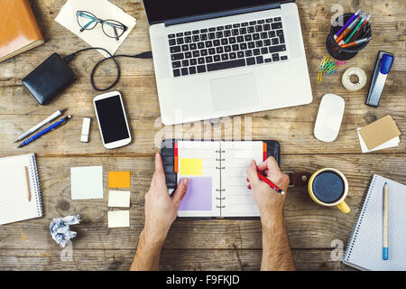 Mix of office supplies and gadgets on a wooden desk background. View from above. Stock Photo