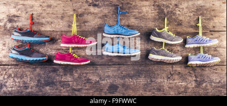 Five pairs of various running shoes hang on a nail on a wooden fence background Stock Photo