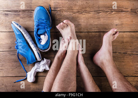 Unrecognizable injured runner sitting on a wooden floor background Stock Photo