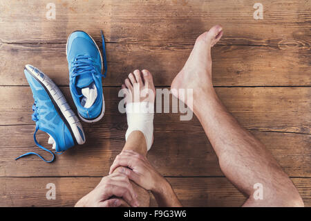 Unrecognizable injured runner sitting on a wooden floor background Stock Photo