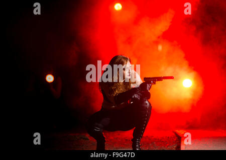 Killer: A young female university student in fancy dress costume as Superhero  assassin 'Black Widow' crouching and shooting a gun Stock Photo