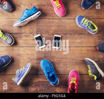 Various running shoes and two smart phones laid on a wooden floor background Stock Photo
