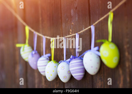 Colorful easter eggs hanging on a twine at the wooden wall background. Stock Photo
