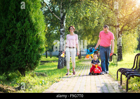 Happy young family walking through the park during a summer day Stock Photo