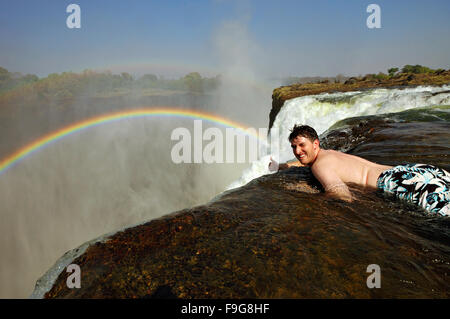 Smiling caucasian man giving thumbs up at the edge of Victoria Falls in Devil's Pool, Zambia Stock Photo