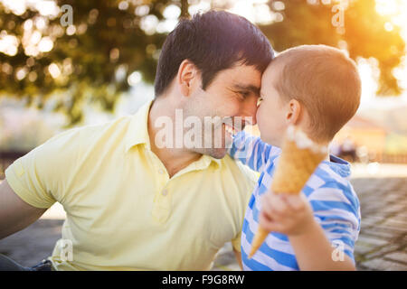 Father and son enjoying ice cream outside in a park Stock Photo