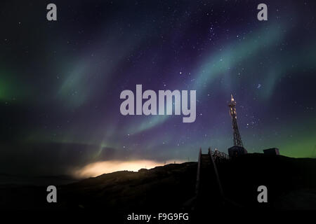 Green extensive Northern lights shining over the starlight sky and telecommunication tower, Nuuk, Greenland, October 2015 Stock Photo