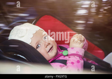 Little baby girl in a car in a child seat Stock Photo
